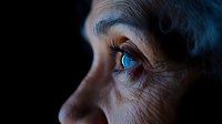 Elderly woman with striking blue eyes in dramatic side lighting showing detailed facial features and natural aging process for healthcare concepts.