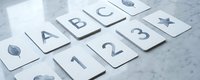Educational flashcards with letters, numbers and nature symbols arranged on marble surface for early childhood learning and development activities.