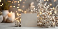 Blank greeting card with white berries, candles and warm bokeh lights creating festive holiday atmosphere for seasonal celebrations and winter decor.