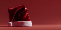 Traditional red Santa Claus hat with white fur trim on burgundy background, festive holiday accessory for Christmas celebrations.