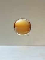 Glowing amber sphere with transparent glass effect floating against neutral background, creating minimalist composition with subtle reflections and shadows.