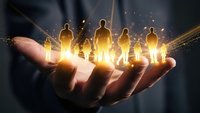 Businessman holding glowing human figures in palm representing team leadership, talent management and human resources development in corporate environment.