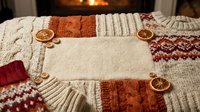 Cozy autumn flat lay with knit sweaters, dried citrus slices, and nuts arranged around blank cream fabric for text or design placement.