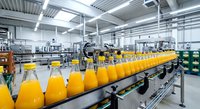 Orange juice bottles moving on automated conveyor belt in modern beverage production facility with industrial equipment and bright lighting.