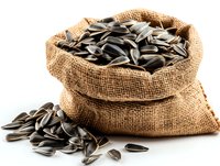 Striped sunflower seeds in burlap sack with scattered seeds on white background, suitable for food packaging and healthy snack advertising.