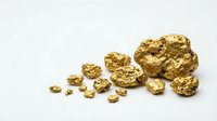 Raw gold nuggets and flakes scattered on white background showing natural precious metal mining treasure for investment and jewelry making.
