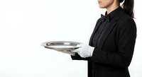 Professional waitress in black uniform holding silver serving tray on white background, hospitality service worker ready for restaurant duties.