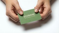 Hands holding green eco-friendly business card with sustainable banking text on white background, corporate identity mockup for environmental finance branding.
