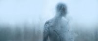 Young adult male with pale skin and light hair, shirtless, depicted as a ghostly or ethereal figure with translucent smoke-like effects merging with misty forest landscape for supernatural or fantasy concepts.