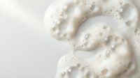 Creamy white foam with bubbles swirling in elegant patterns on neutral background for skincare and beauty product applications.