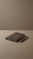 Closed leather notebook with wooden pen on neutral beige background, minimalist business stationery flat lay for corporate branding and office design projects.