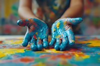 Colorful paint-covered hands against vibrant abstract background, showing creative artistic expression and messy play. Focus on blue paint with yellow and red splashes.