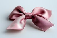 Pink satin bow with elegant loops and tails on light background, macro shot showing silky texture and soft shadows. Isolated decorative element.