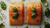 Raw salmon fillets garnished with fresh basil leaves and peppercorns on white background, culinary composition for restaurant menu, food photography.