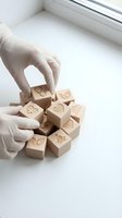 Hands in white gloves arranging wooden emotion blocks with facial expressions for psychology therapy and mental health education concepts.