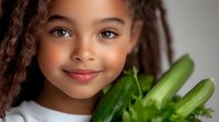 Young African American girl with dreadlocks smiling while holding fresh green celery stalks, promoting healthy eating habits and wellness lifestyle.