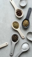Wooden spoons filled with various spices and seasonings arranged on neutral background for culinary cooking and food preparation concepts.