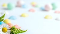 Spring daisy flower with green fern leaves on white background with colorful pastel Easter eggs. Fresh botanical composition for greeting cards.