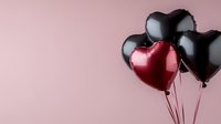 Heart-shaped balloons in black and red colors floating against soft pink background, creating romantic contrast and minimalist composition for Valentine's Day designs.