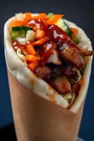 Delicious grilled meat wrap with fresh vegetables and sauce in paper holder, ready-to-eat street food meal for restaurant menu and food delivery service.