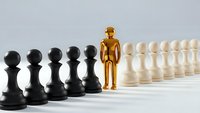Golden figure standing out among black and white chess pawns representing leadership, uniqueness and strategic thinking in business concepts.
