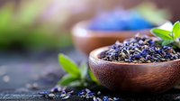 Dried lavender buds in wooden bowl with fresh mint leaves on dark rustic background, aromatic herbs for natural aromatherapy, tea and spa treatments.