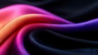 Smooth waves of vibrant silk fabric in gradient colors from black to purple, pink and orange creating elegant flowing curves and luxurious textile texture.