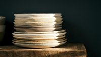 Stack of wooden plates on rustic wooden surface against dark background, suitable for home decor, kitchenware, and interior design projects.