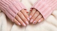 Female hands with pink manicured nails wearing cozy knitted sweater sleeves. Soft pastel colors perfect for beauty, fashion and winter comfort concepts.