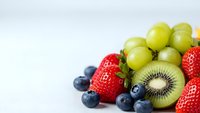 Fresh mixed fruits including strawberries, blueberries, kiwi and grapes arranged on white background for healthy eating and nutrition concepts.