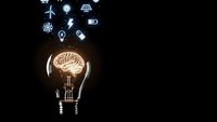Glowing light bulb with brain filament and renewable energy icons on black background representing innovation and sustainable technology solutions.