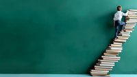 Young Asian male student climbing staircase made of books against green wall background, representing education journey, knowledge growth and academic achievement.