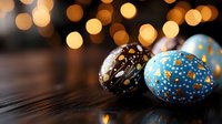 Festive Easter eggs decorated with cosmic pattern in black and blue with gold stars and dots on dark wooden surface against blurred bokeh lights background.