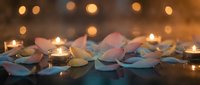 Romantic spa setting with rose petals and glowing candles creating warm ambiance for relaxation and wellness treatments.