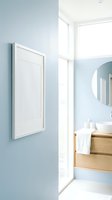 White frame mockup on light blue wall with modern Scandinavian bathroom interior, wooden vanity, round mirror, and natural light.
