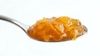 Spoon filled with golden orange marmalade or fruit jam isolated on white background, ready for food packaging and culinary design use.