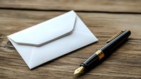 White envelope and luxury fountain pen on rustic wooden table background. Business correspondence and traditional writing concept.