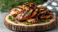 Juicy grilled chicken thighs with crispy charred skin and fresh herbs served on rustic wooden board. Homemade barbecue meat with golden-brown grill marks.