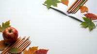 Autumn school supplies with red apple, colored pencils and fall leaves on white background for back to school season and educational projects.