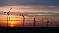 Wind turbines silhouetted against dramatic sunset sky generating clean renewable energy for sustainable power production and environmental conservation.