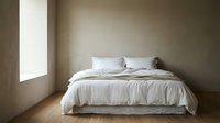 Minimalist bedroom interior with unmade bed featuring white linens, wooden floor, and natural light from window for home decor.