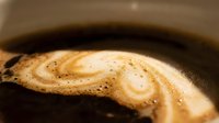 Creamy coffee swirl with foam and bubbles in dark liquid, close-up macro shot for beverage, food photography, and café branding projects.