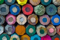 Colorful ends of wooden pencils arranged in rows creating abstract circular pattern. Close-up view shows vibrant colors and natural wood texture. For creative education designs.