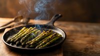 Grilled asparagus spears in cast iron skillet with steam rising, healthy vegetable side dish cooking on rustic wooden table for culinary content.