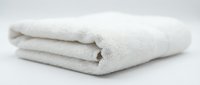 Folded white soft towel on neutral background for spa, hotel, hospitality, laundry, and textile product marketing.