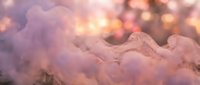 Soft pink and purple smoke clouds with warm golden bokeh lights creating dreamy atmospheric background for romantic designs and creative projects.