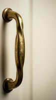 Vintage brass door handle with antique finish on white cabinet door for home renovation and interior design projects.
