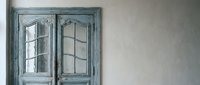 Vintage turquoise wooden cabinet with glass doors and grid pattern against neutral wall in rustic interior design for home decor and furniture styling.
