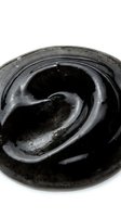 Activated charcoal face mask with swirled texture on white background, ready for beauty and skincare product packaging design.