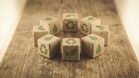 Wooden cubes with green eco symbols including recycling signs and leaves arranged on natural wood surface representing sustainability concepts.